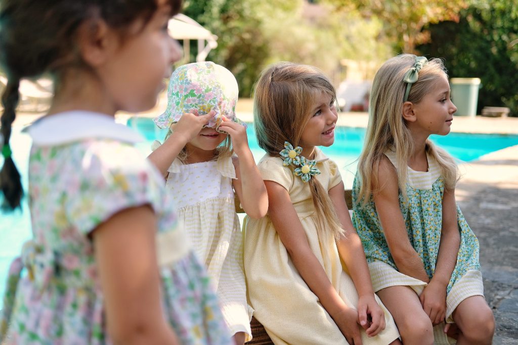 Bambine in abiti a fiori sedute in giardino