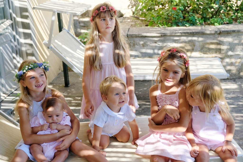 Bambini seduti insieme con abiti sartoriali bianchi e rosa